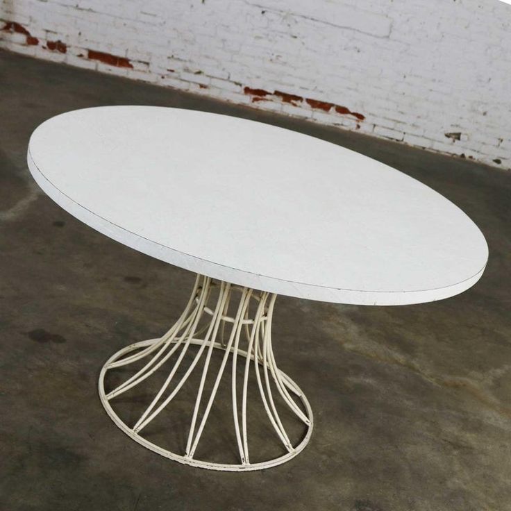 a white table sitting on top of a cement floor next to a brick wall in an empty room