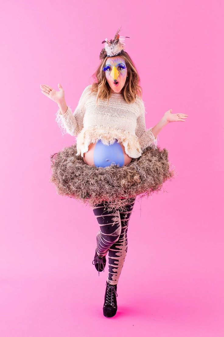 a woman in tights and boots is sitting on top of a fake bird's nest