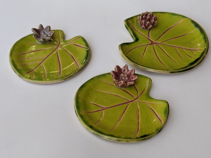 three green leaf shaped dishes with flowers on them