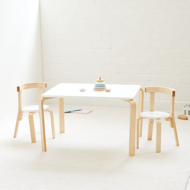 two children's wooden chairs sitting at a white table with a toy on it