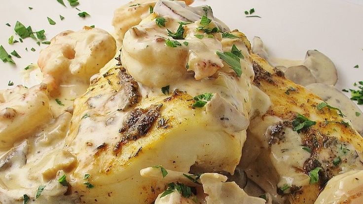 some chicken and potatoes are covered in gravy on a white plate with parsley