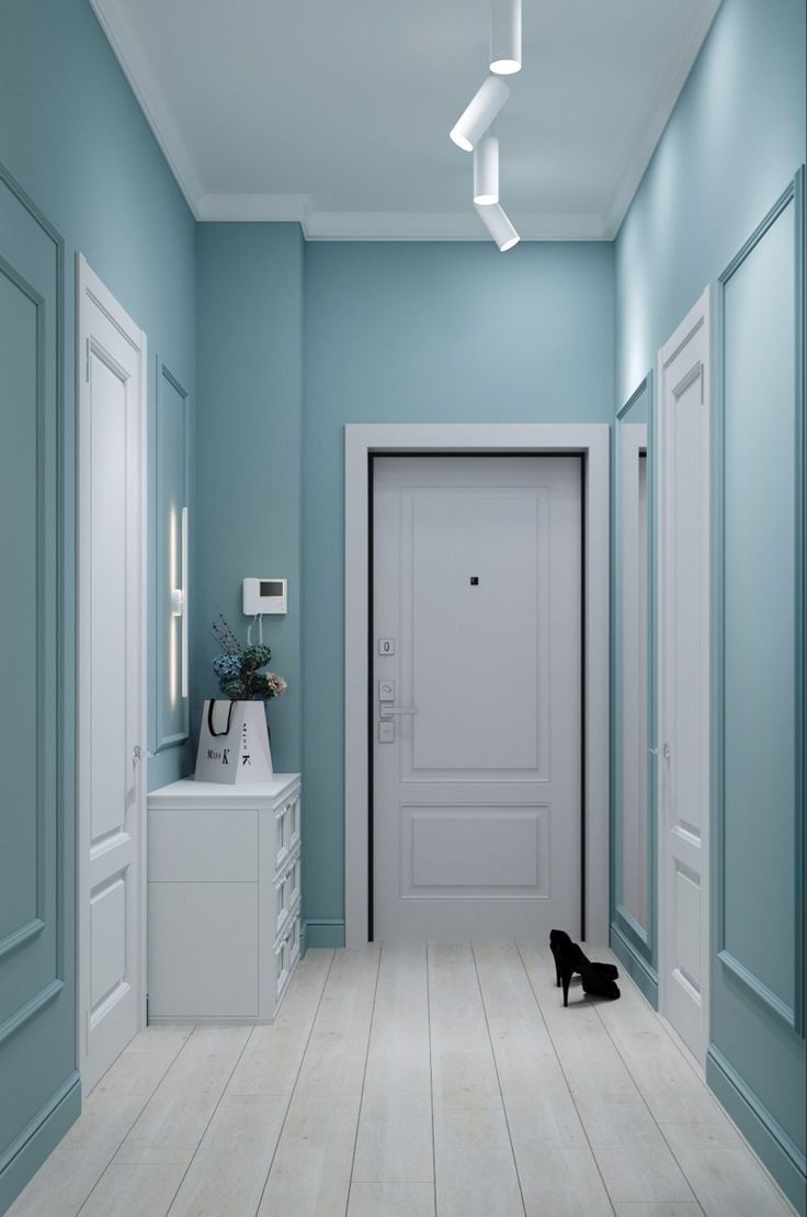 an empty hallway with blue walls and white trim on the doors, floors and cabinets