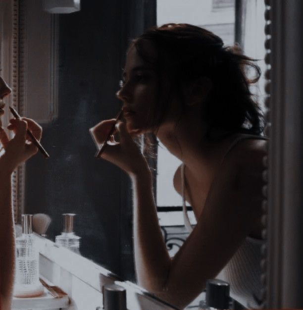 a woman is brushing her teeth in front of a mirror while looking at herself in the mirror