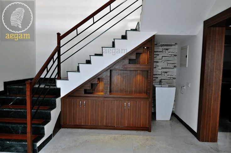 an empty room with stairs and wooden cabinets