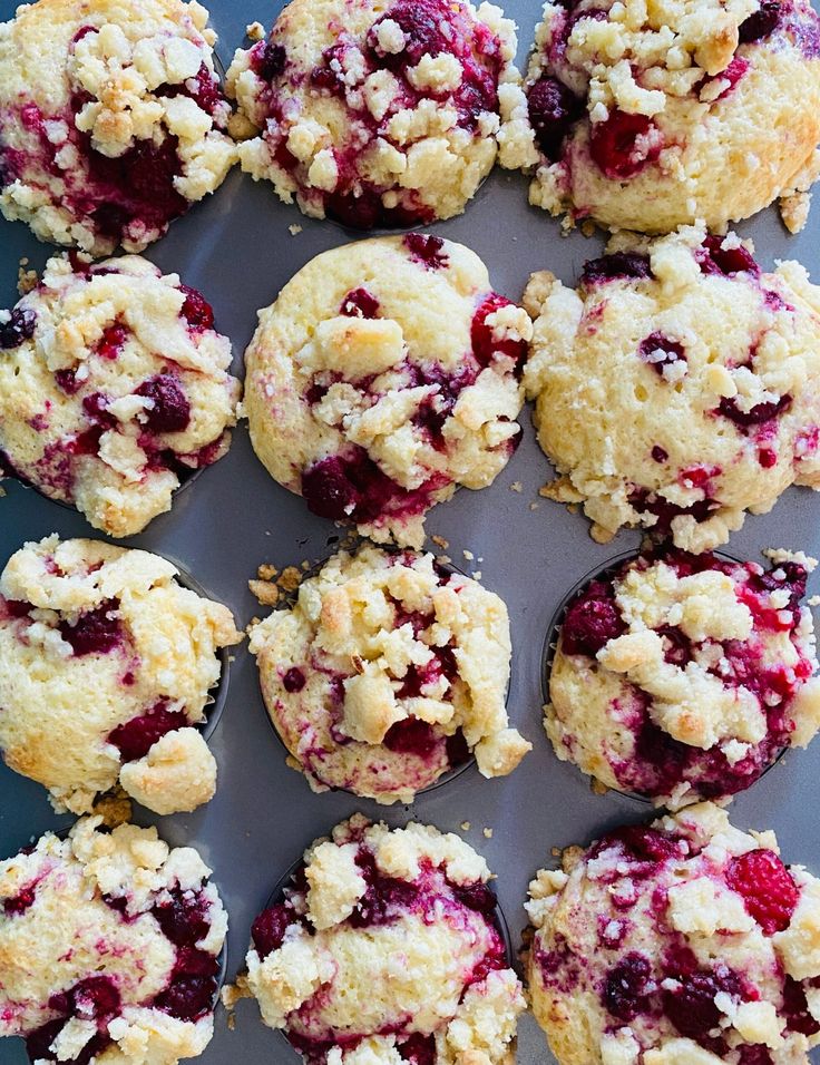 muffins with crumbs and powdered sugar are arranged on a baking sheet