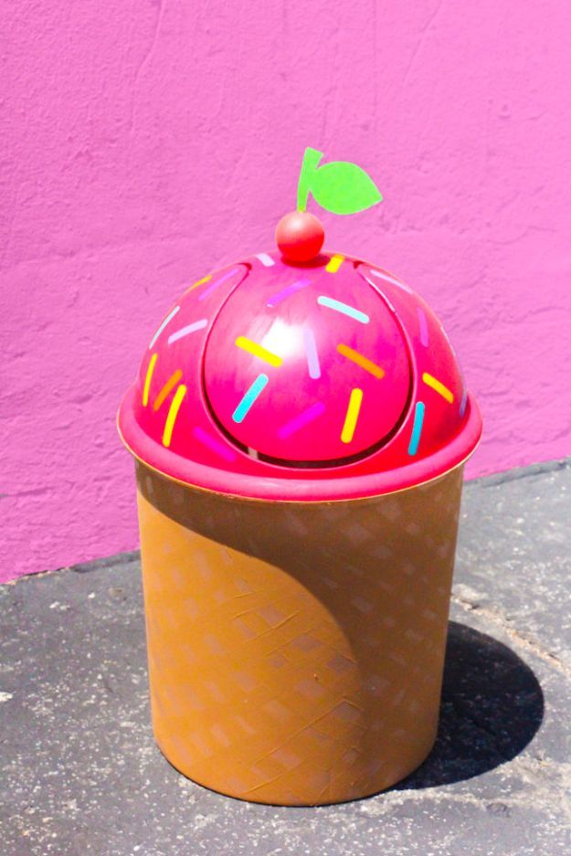 an ice cream cone with sprinkles and a cherry on top is sitting in front of a pink wall