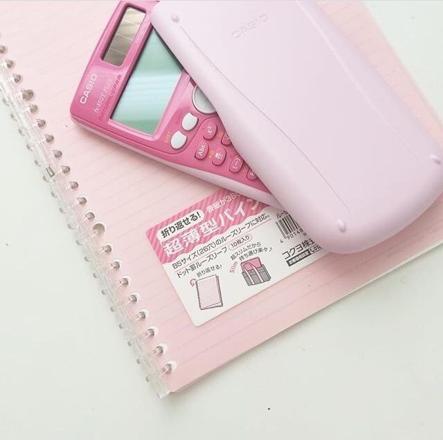 a pink cell phone sitting on top of a notepad next to a plastic case