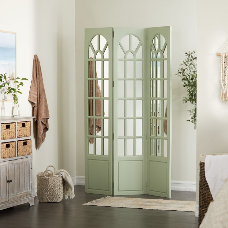 a room with white walls and wooden floors has an open green door to the bedroom