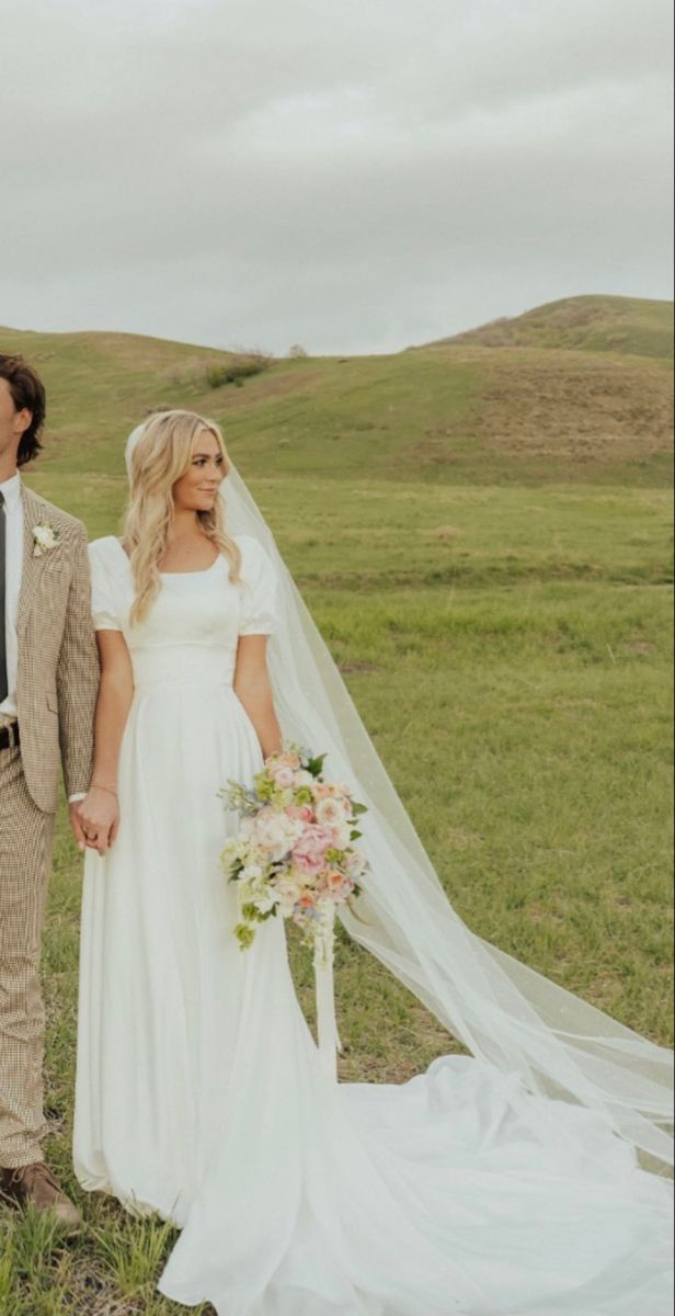 a bride and groom standing in the grass