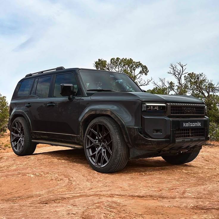 a black land rover is parked in the dirt