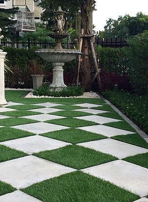 a white and black checkerboard pattern is in the grass next to a fountain