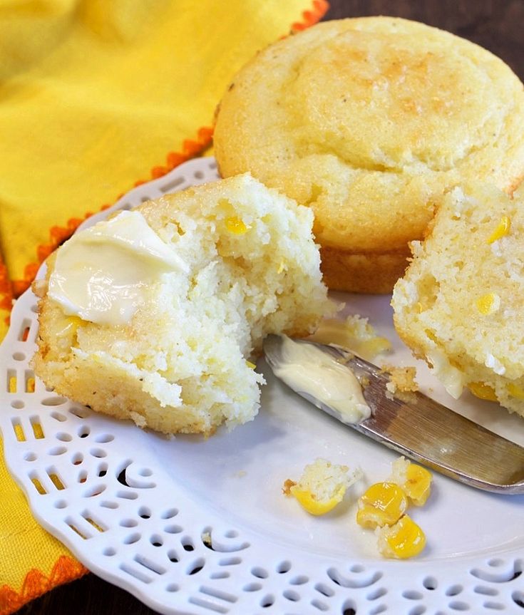 a white plate topped with two muffins covered in frosting next to a knife