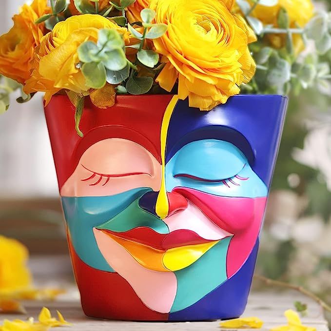 a colorful vase with yellow flowers in it and a face painted on the front side