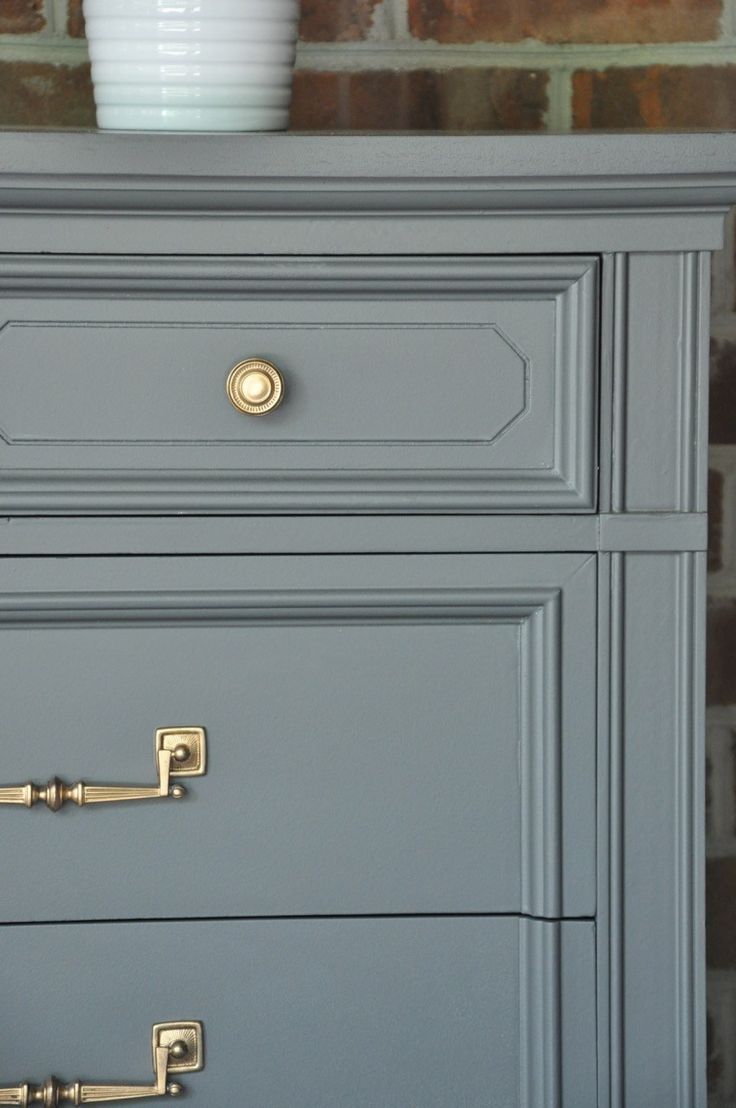 a gray dresser with brass handles and knobs