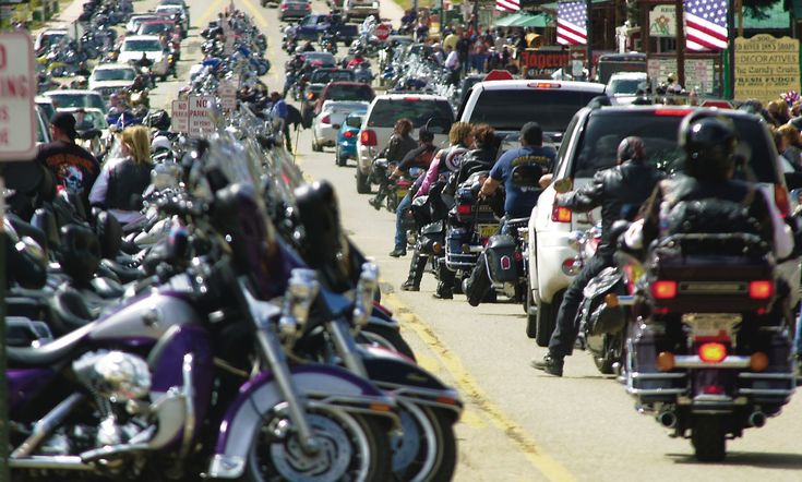 a large group of motorcyclists are riding down the street in front of cars