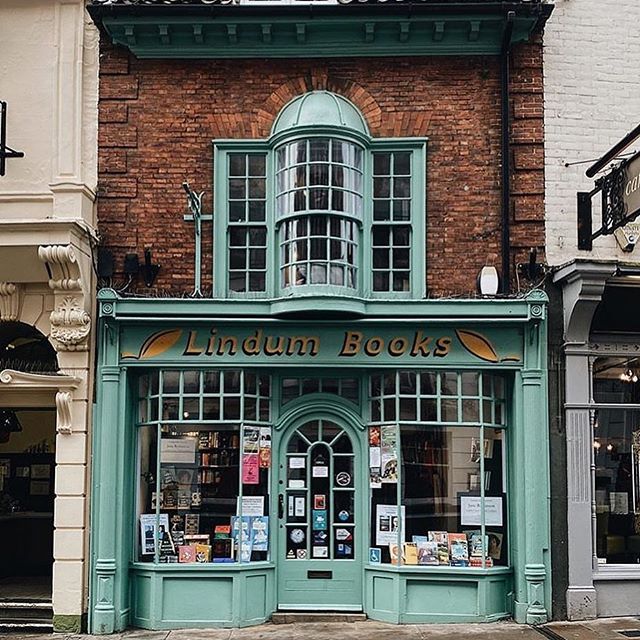 an old brick building with green shutters on the front and windows that read linden books