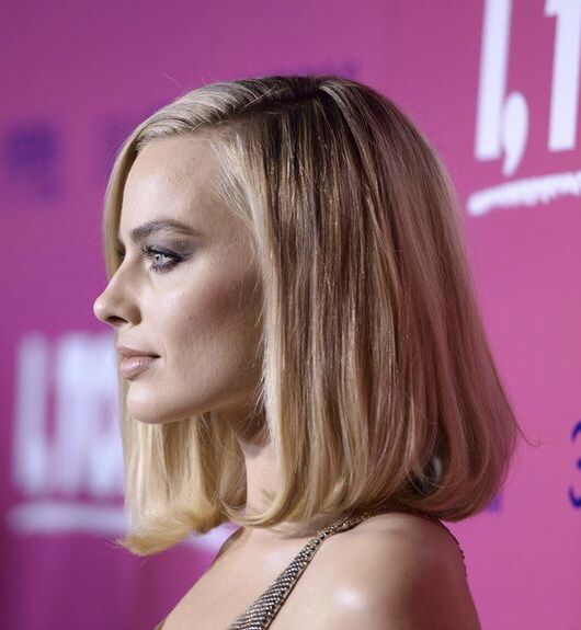 a woman with blonde hair and blue eyeshadow wearing a black dress at an event