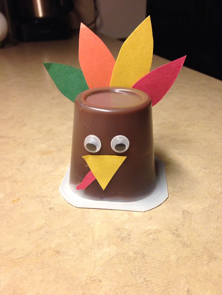 a chocolate cup with a paper turkey on it's head sitting on a counter