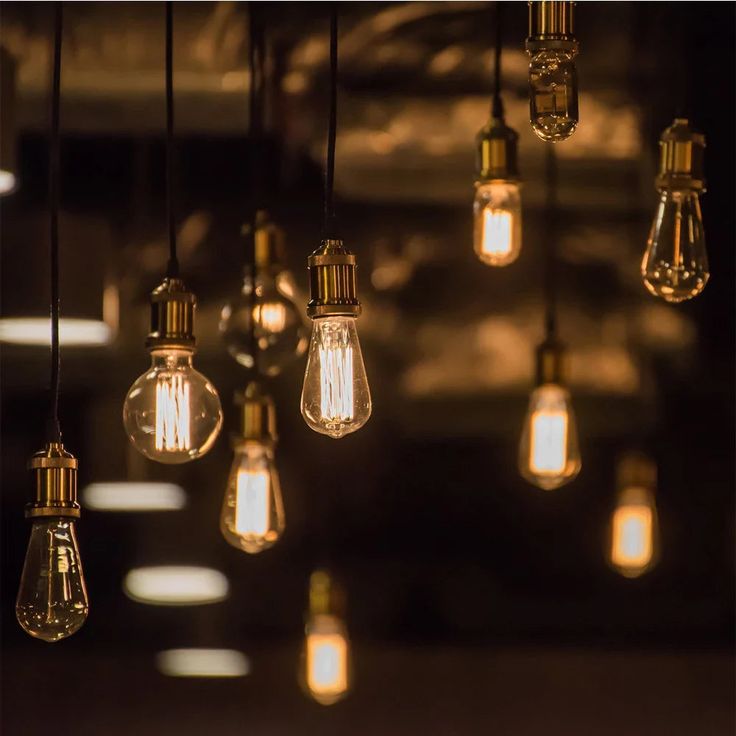 several light bulbs hanging from the ceiling in a dark room with other lights on it