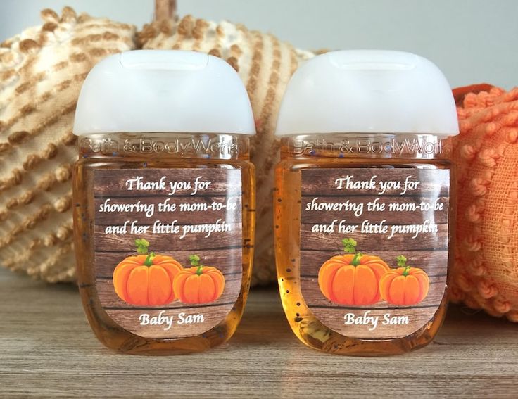 two bottles of baby sun lotion sitting on top of a wooden table next to an orange pumpkin