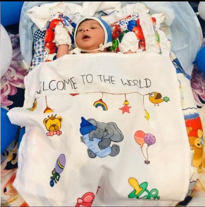 a baby laying in a bed with a welcome to the world blanket