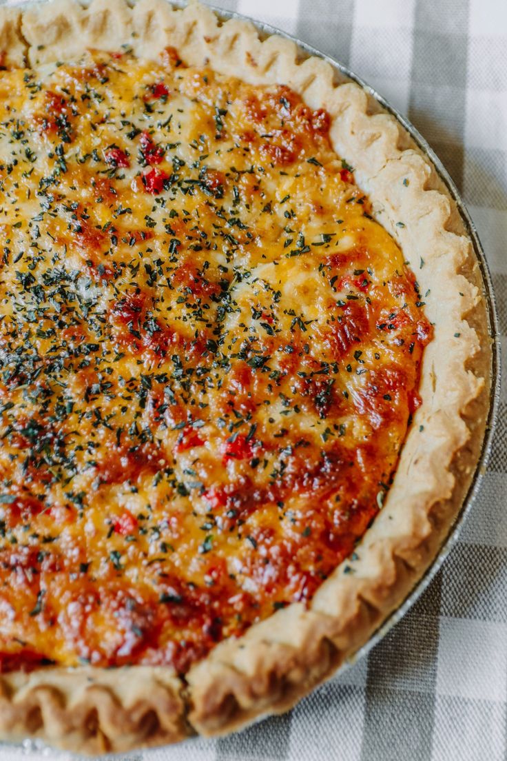 a cheesy pizza sitting on top of a checkered table cloth