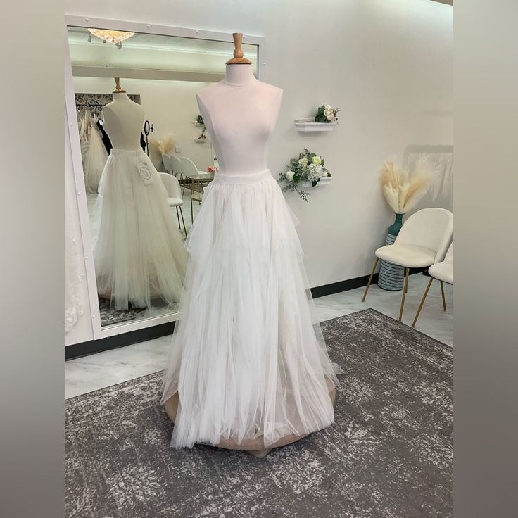 a white dress is on display in front of a mirror and some other mannequins