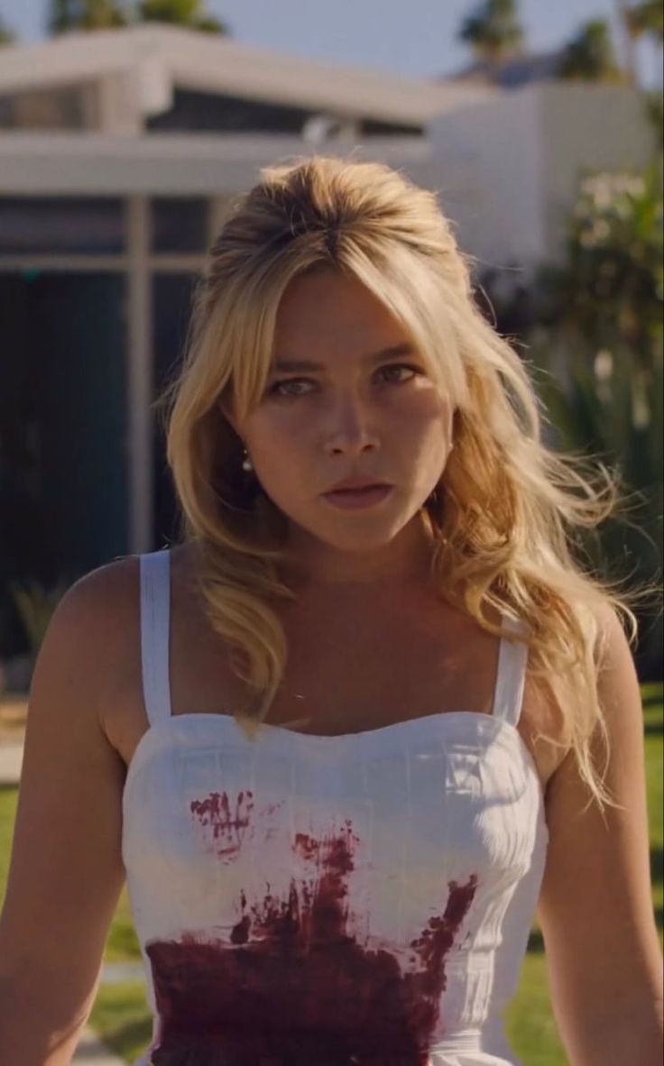 a blonde woman in a white top and red paint splattered on her body