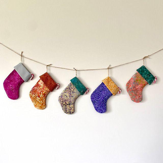 christmas stockings hanging from a line on a white wall