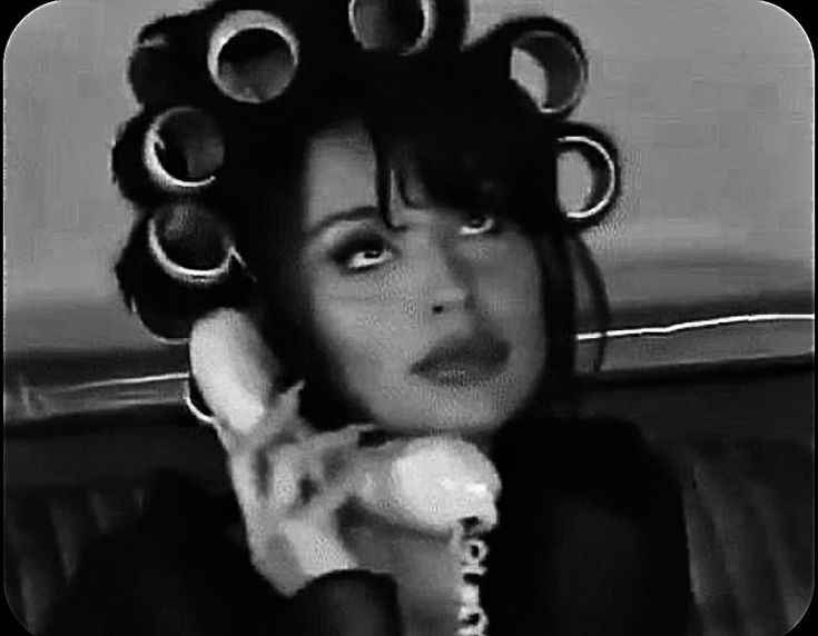 a woman with curlers on her head is talking on the phone and holding a telephone