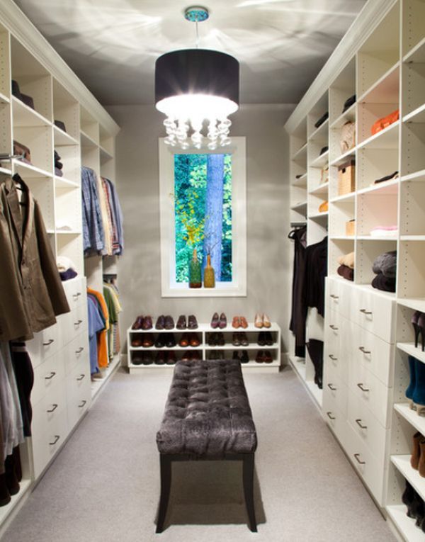 a walk in closet with white shelving and shelves