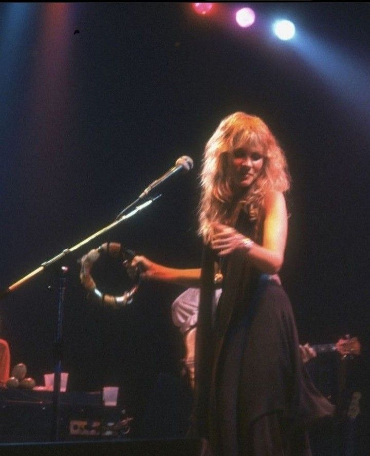 a woman standing in front of a microphone on stage