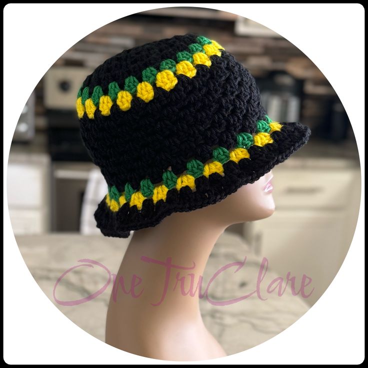 a crocheted hat with yellow and green flowers on the brim, sitting on top of a mannequin head