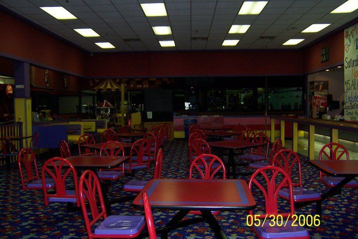 an empty restaurant with red and blue chairs, tables and booths in the center area