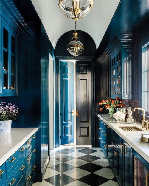 a kitchen with blue cabinets and marble counter tops, along with a checkered floor