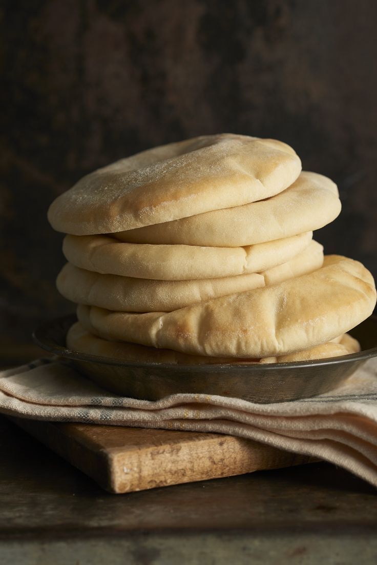 a stack of white bread sitting on top of a wooden cutting board