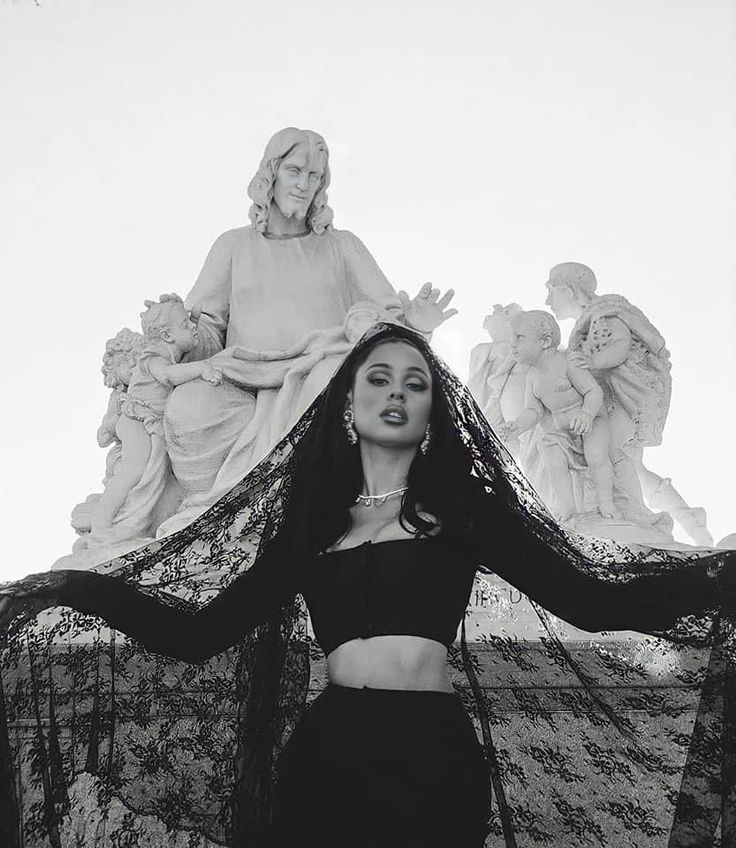 a woman standing in front of a statue with her arms spread out to the side