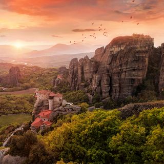 an aerial view of the rocky landscape with trees and mountains in the background at sunset