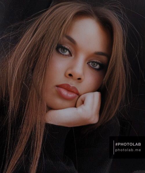 a woman with long brown hair and blue eyes posing for a magazine cover, she has her hand on her chin