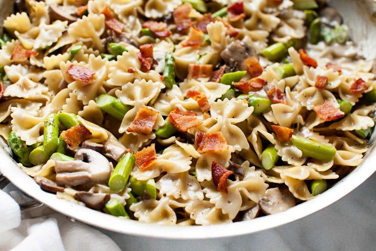 a bowl filled with pasta and vegetables on top of a marble countertop next to a white towel