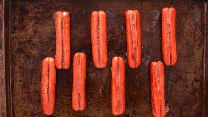 six hotdogs on a baking sheet ready to be cooked in the oven for dinner