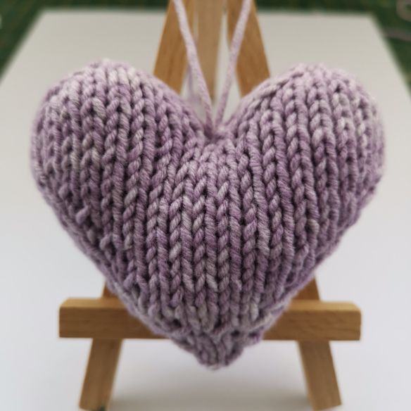 a knitted heart sitting on top of a wooden easel