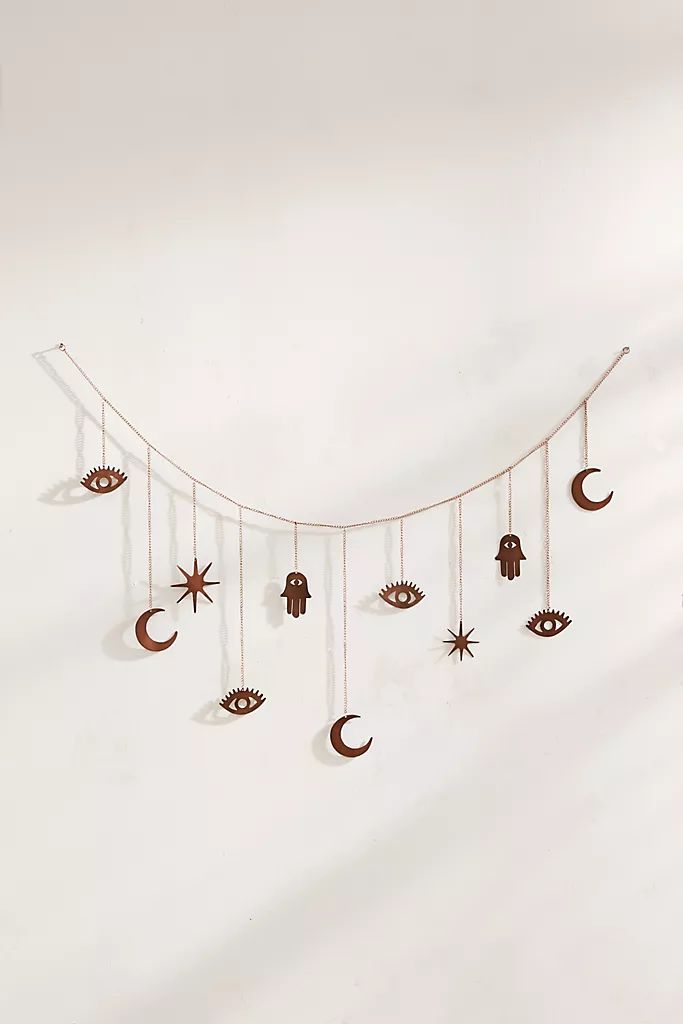 an artistic wall hanging made out of paper and string with eyes, hands, stars and moon on it