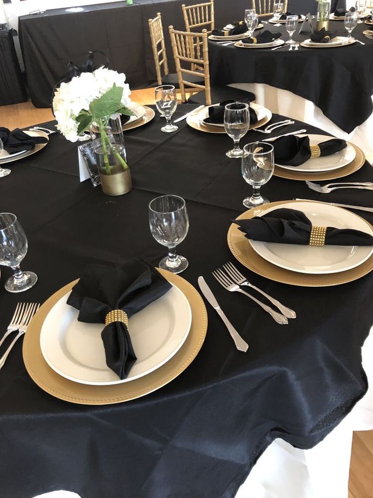 the table is set with black and gold place settings