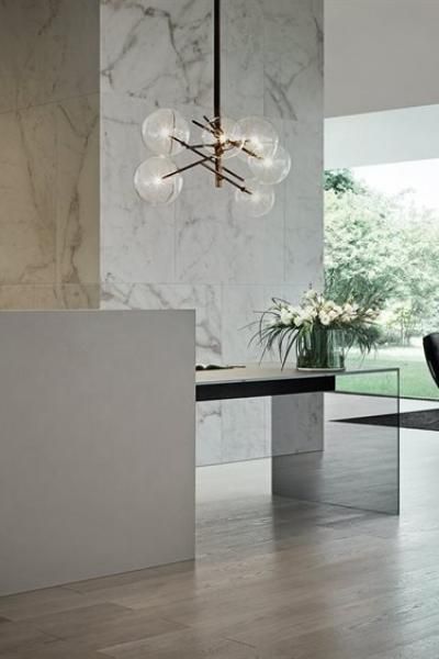 an elegant dining room with marble walls and flooring, glass chandelier above the table