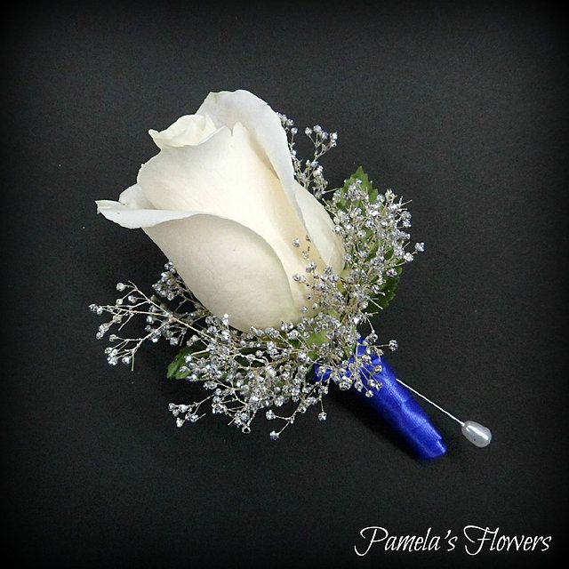 a white rose and baby's breath boutonniere on a black background