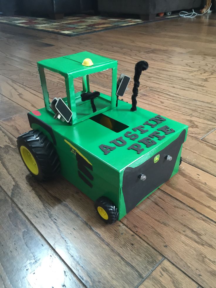 a green toy tractor sitting on top of a hard wood floor