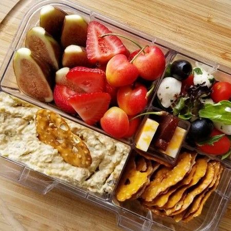 a plastic container filled with fruit and crackers