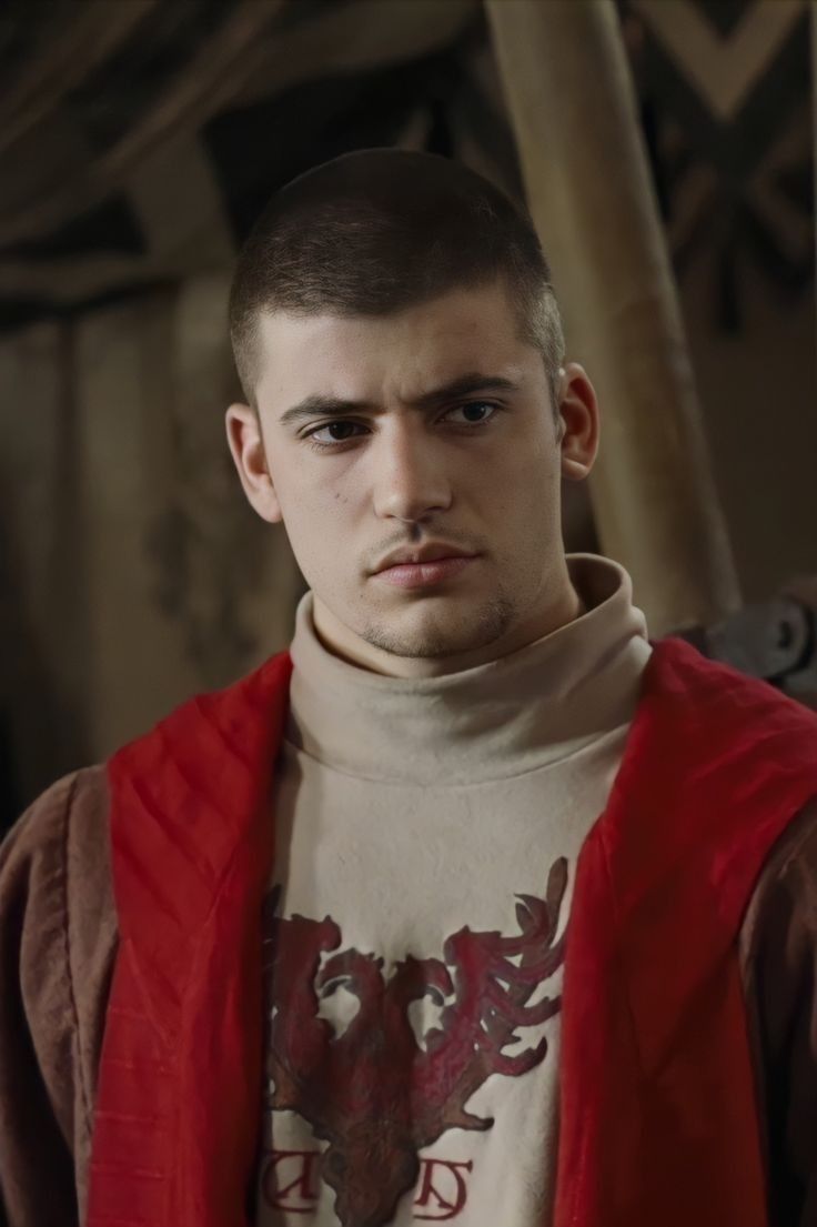 a young man wearing a red vest and looking at the camera