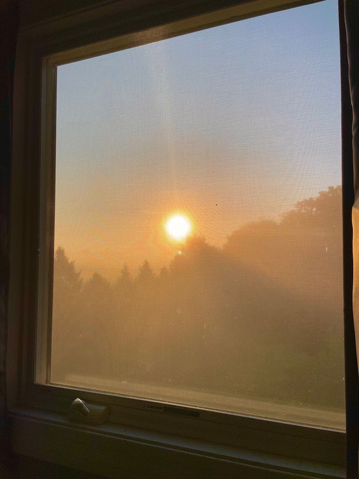 the sun is shining through the foggy window pane, with trees in the background